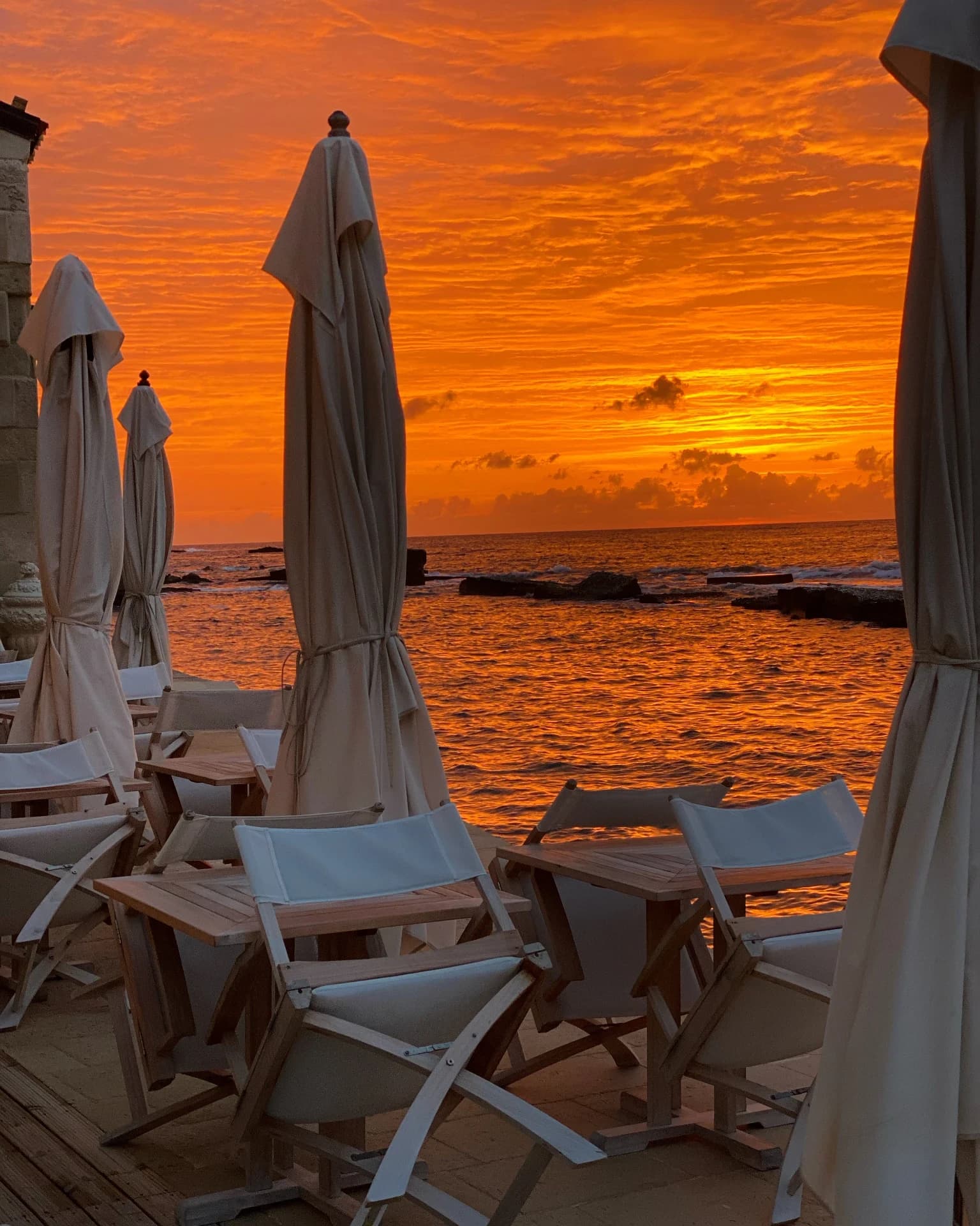 Strand bei Sonnenuntergang mit Liegen und Sonnenschirmen