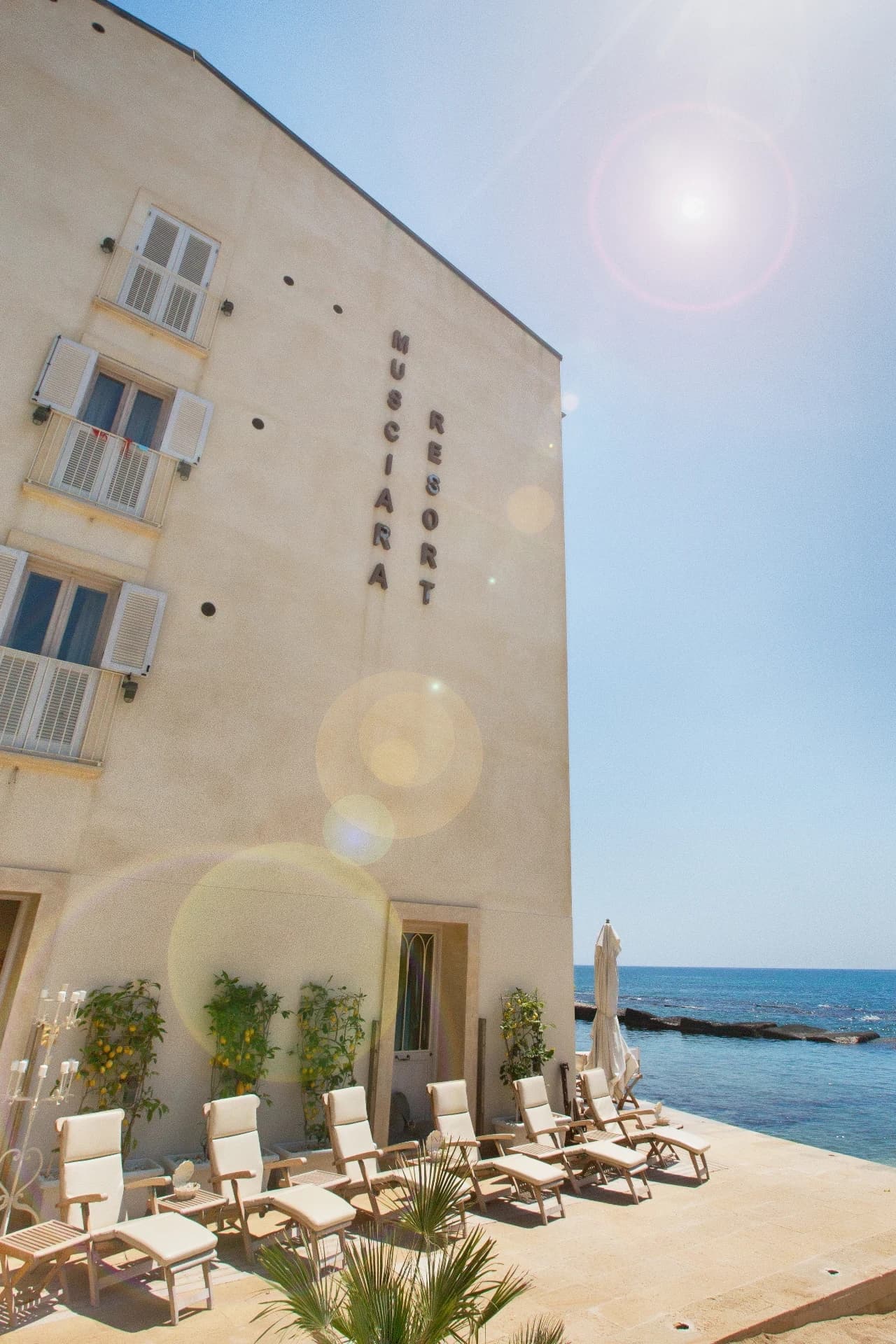 Resortfassade mit Liegen am Meer
