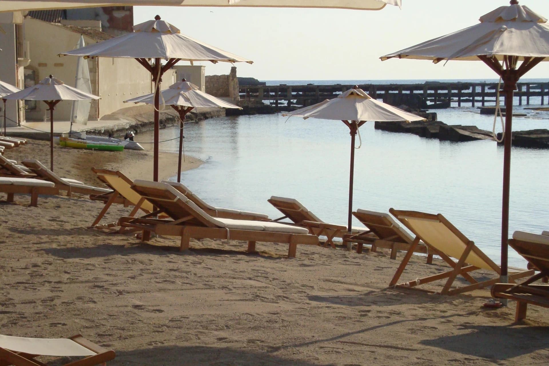 Strand des Musciara Resort mit Sonnenschirmen und türkisfarbenem Meer